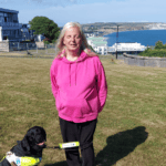 Emily Brothers and her guide dog, Truffle, with View of Sandown Bay in the background