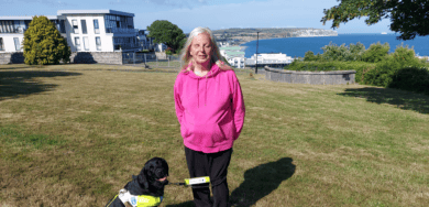 Emily Brothers and her guide dog, Truffle, with View of Sandown Bay in the background