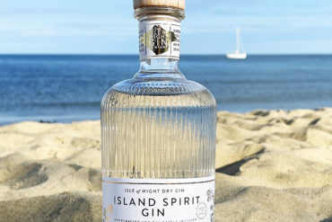 Isle of Wight gin bottle on the beach with sea in the background