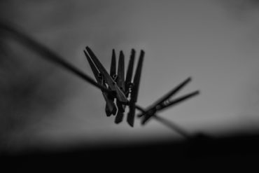 black and white image of clothes pegs on a washing line