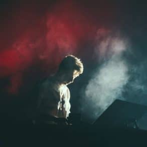 man playing the electronic organ on stage with smoke around him