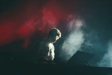 man playing the electronic organ on stage with smoke around him