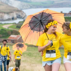 people on walk the wight with yellow umbrellas and sunflowers