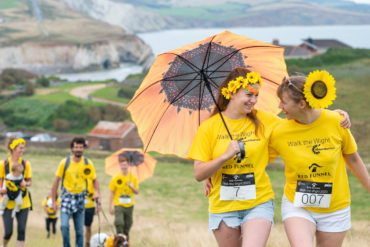people on walk the wight with yellow umbrellas and sunflowers