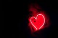 person holding a neon love heart in the dark