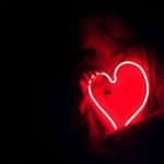 person holding a neon love heart in the dark
