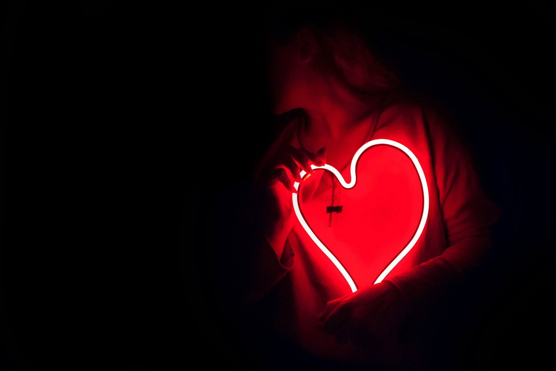 person holding a neon love heart in the dark