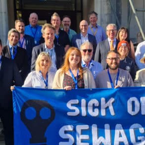 Councillors outside county hall holding a 'sick of sewage' banner