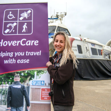 Hovertravel staff holding a banner by the hovercraft