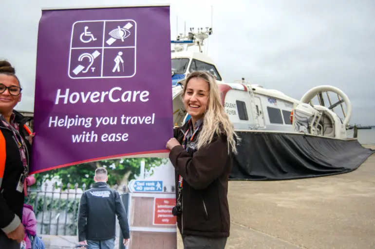 Hovertravel staff holding a banner by the hovercraft
