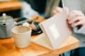 Person with mug of tea and writing in notepad