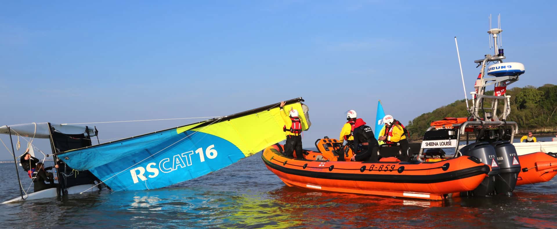 RNLI volunteers in rib rescuing people on a catamaran - UKSA