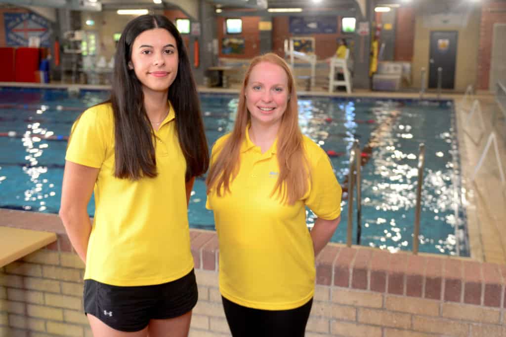 West Wight Sports & Community staff Izzy Taylor Receptionist, Lifeguard and Instructor and Emily Mann Fitness Instructor by the Swimming Pool