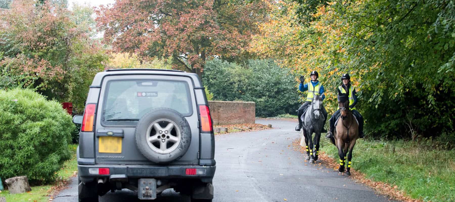 Riders on the road with car passing slowly