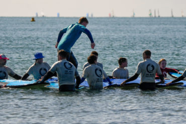 Participants running across a bed of surf boards lined up on the water