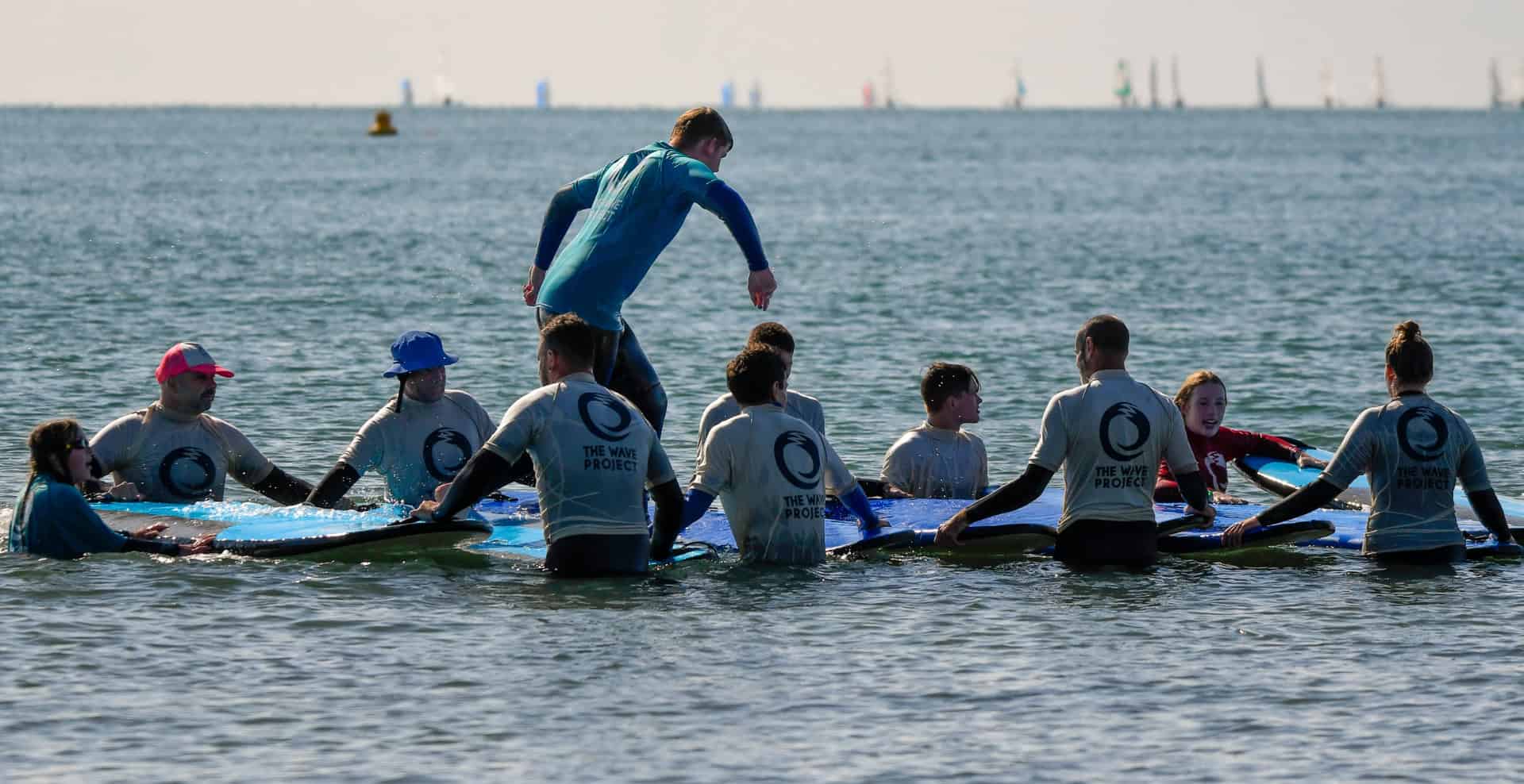 Participants running across a bed of surf boards lined up on the water