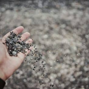 person dropping gravel through their hand