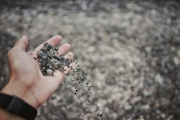 person dropping gravel through their hand
