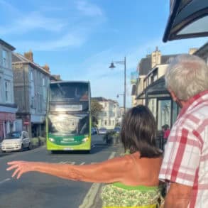 two older people flagging down a bus in Sandown
