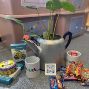 Teapot with plant in it, games and sweets