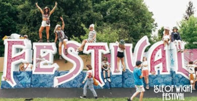 IW Festival lettering with people sat on it