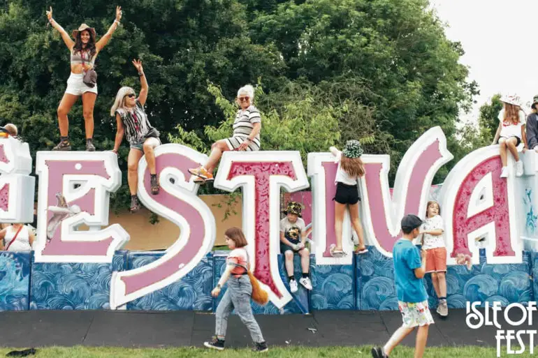 IW Festival lettering with people sat on it