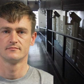 Mugshot of Dan Taylor with jail corridor in background