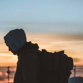 silhouette of man with large rucksack on his back with sunset in the background by dimi katsavaris