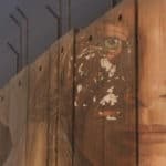 Grab from the film showing the wall in the West Bank with graffiti of a woman's face on it