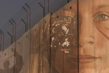 Grab from the film showing the wall in the West Bank with graffiti of a woman's face on it