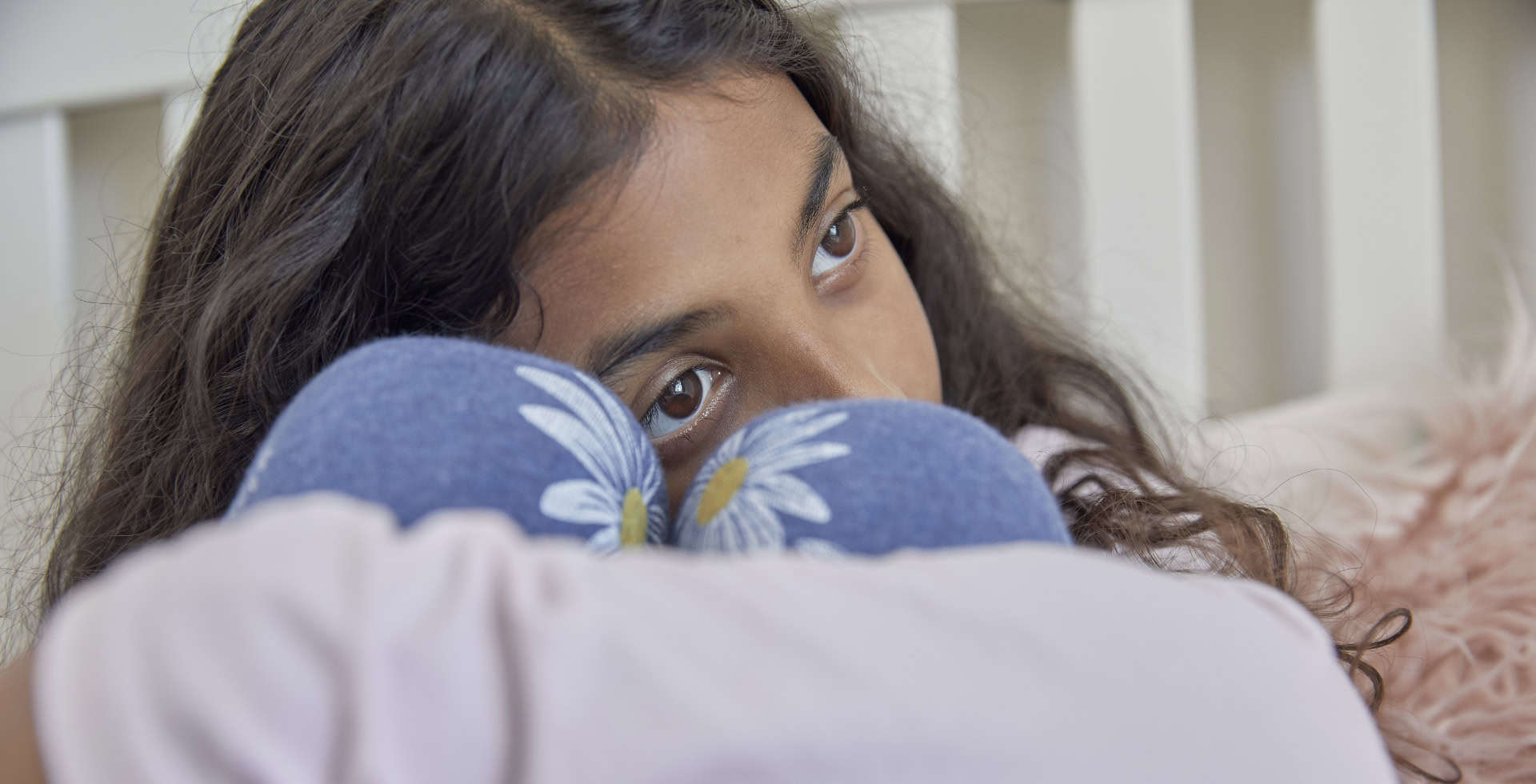 Young female teenager sat with her knees bent up in front of her, hugging them