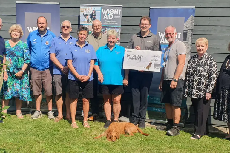 People standing outside a building with a giant cheque from Wight Aid