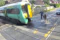 Two people rushing across the level crossing narrowly missed by the oncoming train