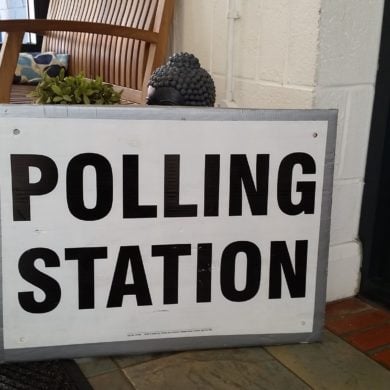 Polling station sign in front of a buddha statue