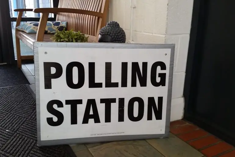 Polling station sign in front of a buddha statue