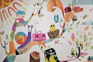 Wallart showing a child sitting on a branch of a tree, surrounded by animals and birds