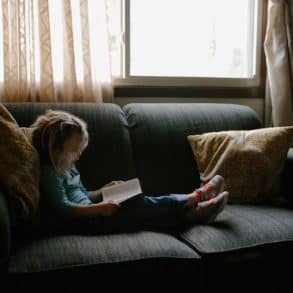 child on a sofa reading a book
