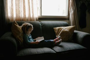 child on a sofa reading a book