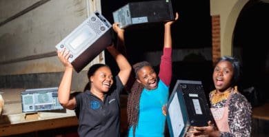 children in africa holding up laptops and smiling