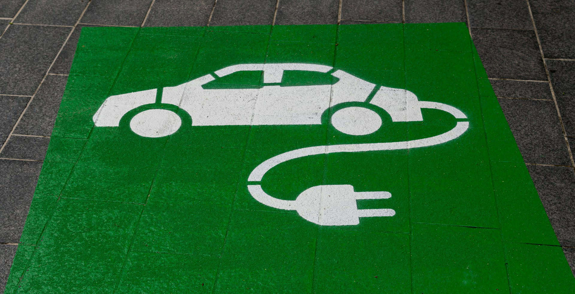 green paint on pavement with electric car symbol