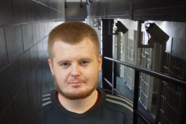 Mugshot of Harry White with jail corridor in background