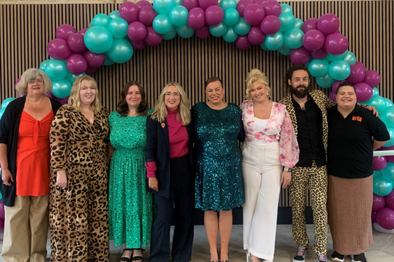 Staff and those who helped make this a reality standing by arch of balloons