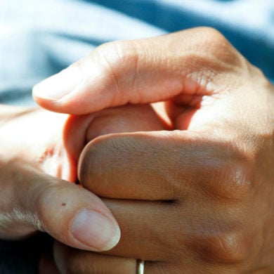 A carer holding the hand of a patient