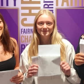 Female students holding their GCSE results up