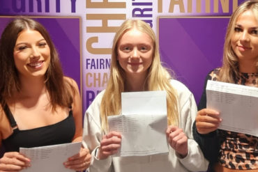 Female students holding their GCSE results up