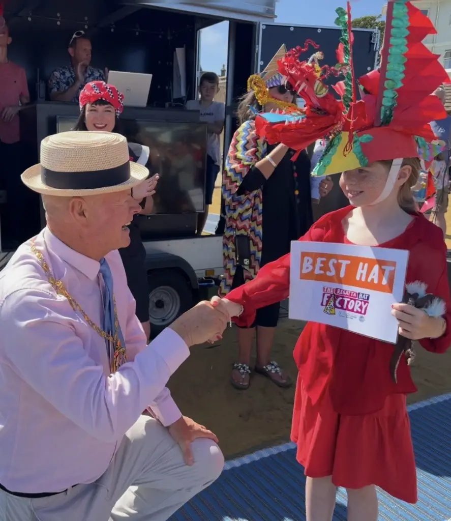 Isle of Wight Council Chair Karl Love congratulates Sandown Hat Factory regular Freya, overall winner for Best Regatta Hat (photo by Sandown Carnival)