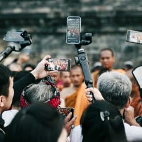 Paparazzi crowd of photographers surrounding buddhists