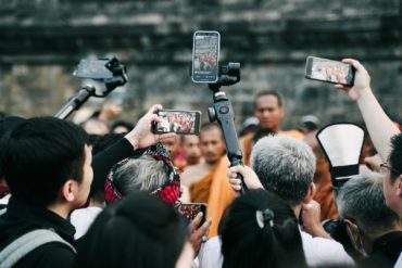 Paparazzi crowd of photographers surrounding buddhists