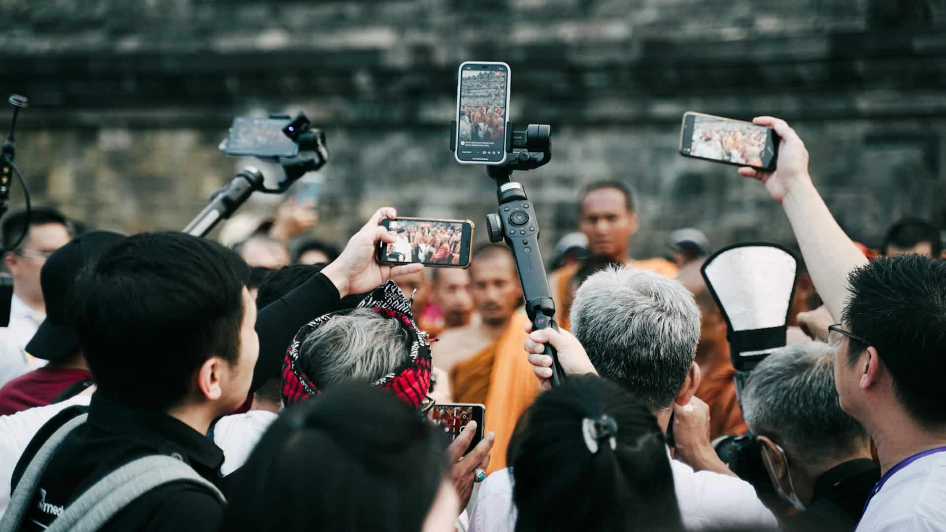 Paparazzi crowd of photographers surrounding buddhists