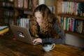 Teenage girl sitting in a library at a laptop